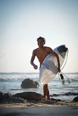 LMBK Surf House Surf Instructor with surfboard on the beach in Kuta Lombok